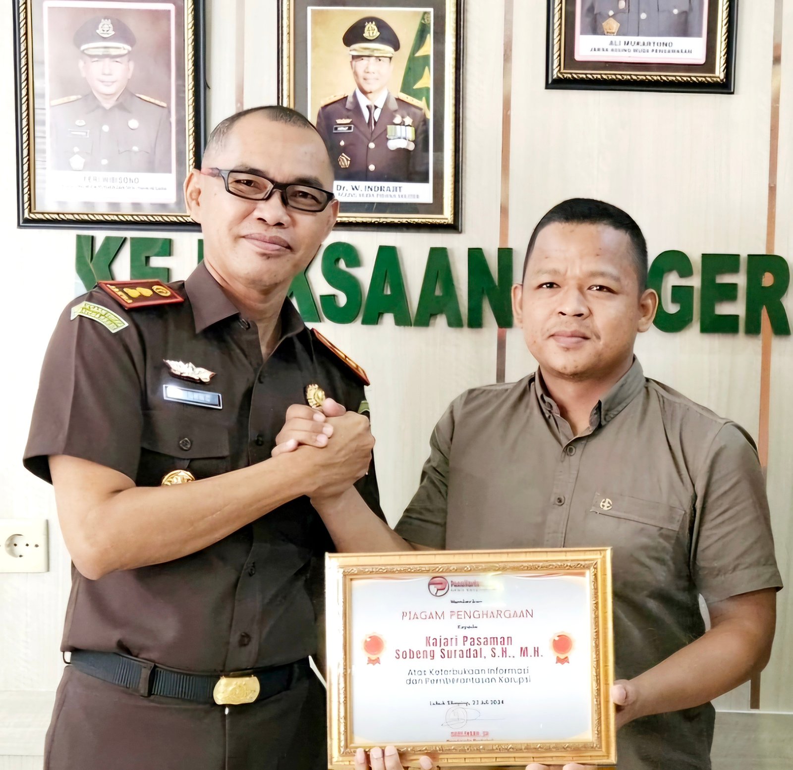 Pemimpin Redaksi PenaHarian.com, Darlinsah, SH memberikan piagam penghargaan kepada Kajari Pasaman Sobeng Suradal, SH., M.H. di ruang kerja Kajari pada hari Rabu, 24 Juli 2024.